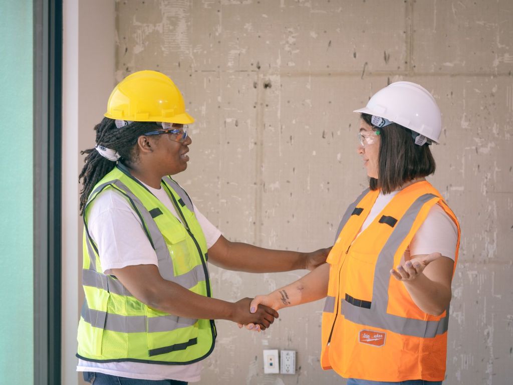 Zwei Handwerker geben sich auf der Baustelle die Hand